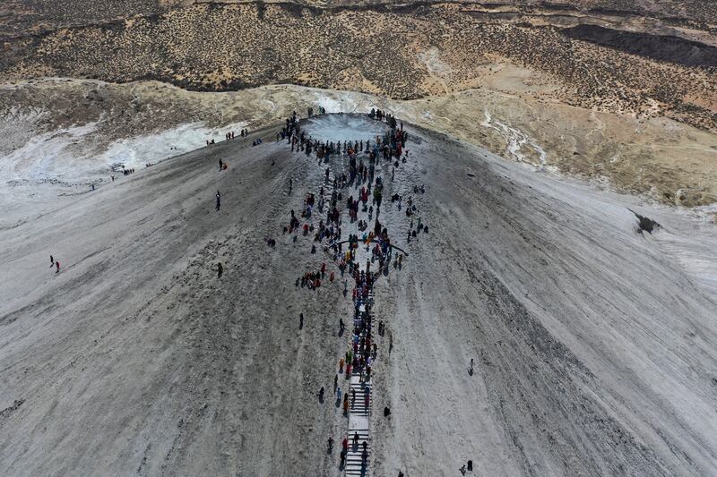 Devotees climb to the top of a mud volcano to start rituals for an annual Hindu festival in Balochistan province, Pakistan. AP 