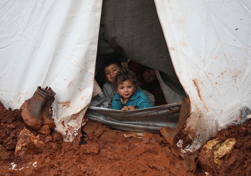Syrian children sit in their tent look out at the muddy path at the Cordoba camp. AFP