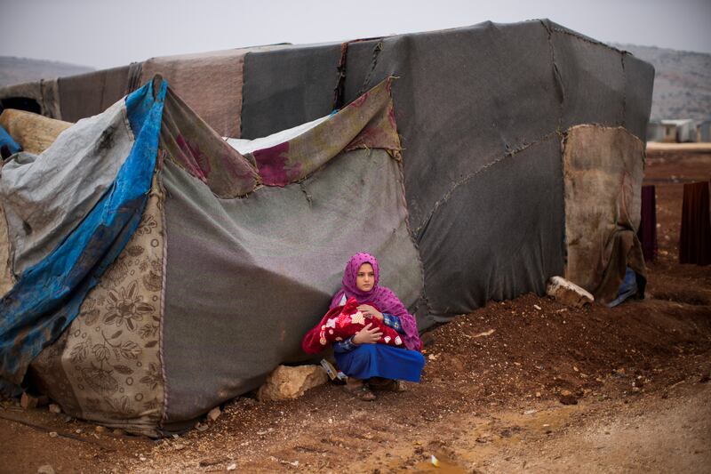 A young Syrian woman holds a baby at a refugee camp for displaced people in Sarmada district, north of Idlib city, in Syria. The fallout from the Ukraine war is worsening long-term humanitarian crises elsewhere, including in Syria. AP