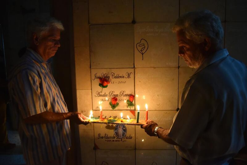 People light candles next to the grave of a relative in a cemetery during the traditional 'Night of candles' in Cali, Colombia.  Thousands of Colombian families crowded the streets today with lanterns and candles to start the Christmas season with the celebration of the traditional 'Night of candles' prior to the Immaculate Conception.  EPA