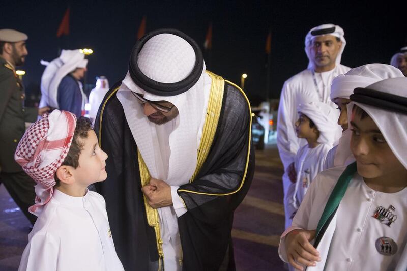 Sheikh Mohammed bin Zayed, Crown Prince of Abu Dhabi Deputy Supreme Commander of the Armed Forces (C) greets a young guest during the 44th UAE National Day celebrations at Zayed Sports City. Mohamed Al Hammadi / Crown Prince Court - Abu Dhabi