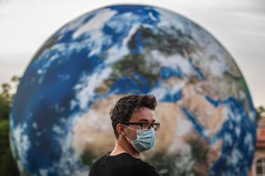 epa08682665 A man wearing protective face mask stands in front of the giant inflatable model of the Earth during European Sustainable Development Week, as well on World Clean Up day, at the garden of Czech Ministry of Foreign Affairs in Prague, Czech Republic, 19 September 2020. Through this event, the Czech Foreign Ministry wants to present a country as active in matters of sustainability and climate. EPA/MARTIN DIVISEK