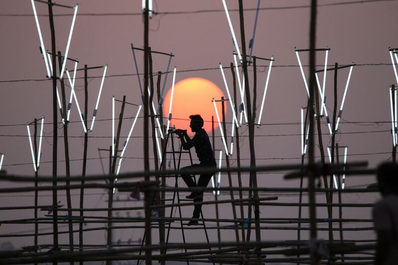 A worker installs lights at an outdoor location for a film shoot in Bhopal, India. AFP
