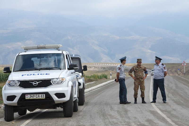 Armenian law enforcement officers guard a road near the entrance to the Lachin corridor, Karabakh's only land link with Armenia, on August 30. AFP