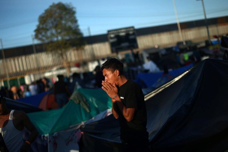 A migrant, part of a caravan of thousands from Central America trying to reach the United States, rubs his hands inside a temporary shelter in Tijuana, Mexico. Reuters