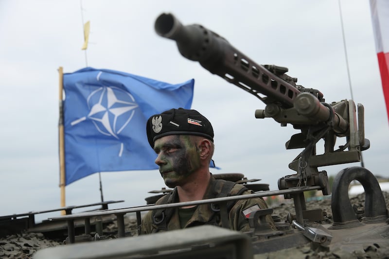 A Polish soldier in a tank as the Nato flag flutters behind him. Getty