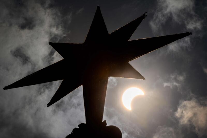 The moon begins to cover the sun, as seen behind a Christmas tree star in Bangkok, Thailand.  AFP