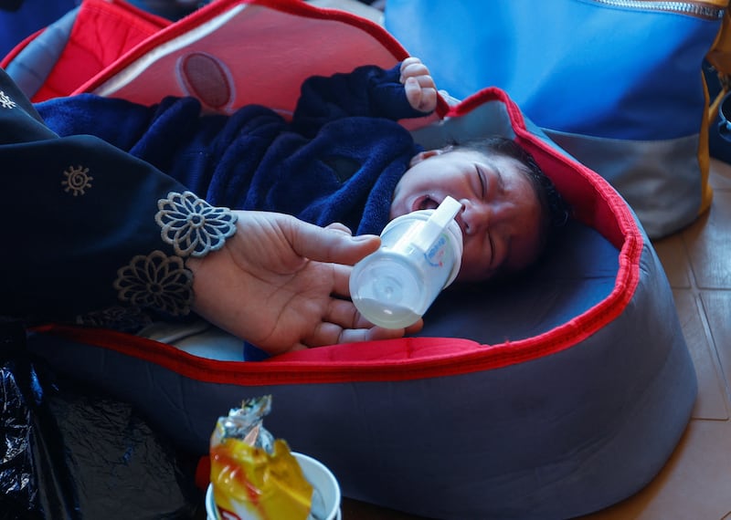 A baby is fed amid the war, while those with dual citizenship await for permission to leave Gaza. Reuters