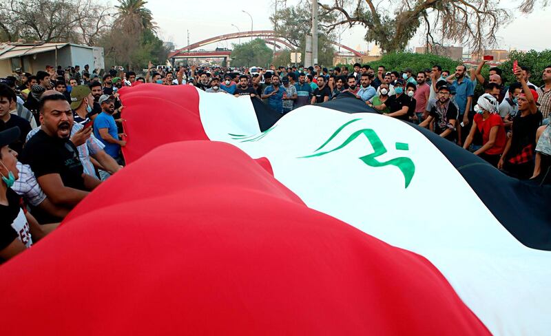 Iraqi protesters hold a national flag during a demonstration demanding better public services and jobs in Basra. AP
