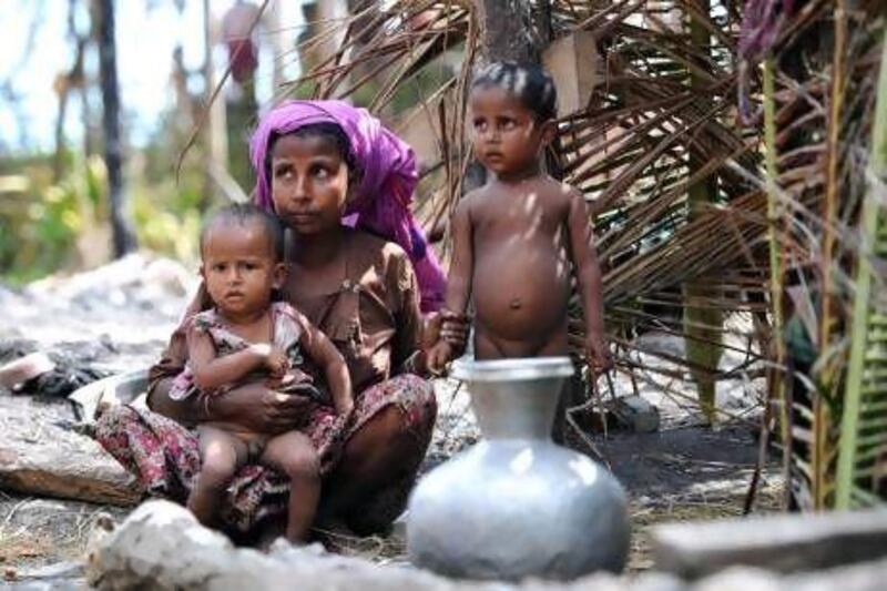 A Rohingya Muslim woman sits with her children outside a temporary shelter at a village in Minpyar in Rakhine state. Homeless people fled to packed camps or clustered near their charred houses amid ongoing unrest.