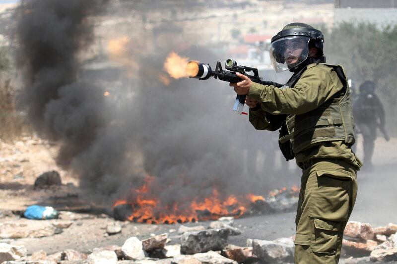 An Israeli border policeman fires teargas towards Palestinian demonstrators during a protest against the expansion of the nearby Jewish settlement of Kdumim, in the northern West Bank village of Kufr Qaddum, Friday, July 6, 2012. (AP Photo/Nasser Ishtayeh)