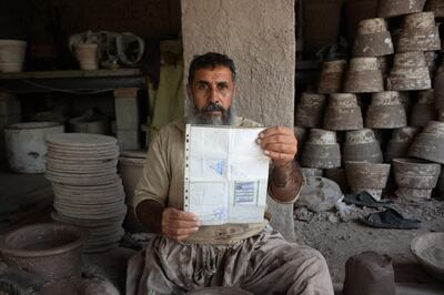 In this photo taken on October 10, 2018.Afghan potter Shirin Agha, 45, poses for a picture as he holds his id card or Tazkira registered to vote in the upcoming parliamentary election at his workshop, on the outskirts of Jalalabad. Bloody violence has forced thousands of polling centres to close and stopped millions of people from registering to vote. But war-torn Afghanistan's long-delayed legislative election will still go ahead on October 20, officials say. Almost nine million people are eligible to vote in the ballot, which is more than three years late and largely funded by the international community.
 / AFP / NOORULLAH SHIRZADA
