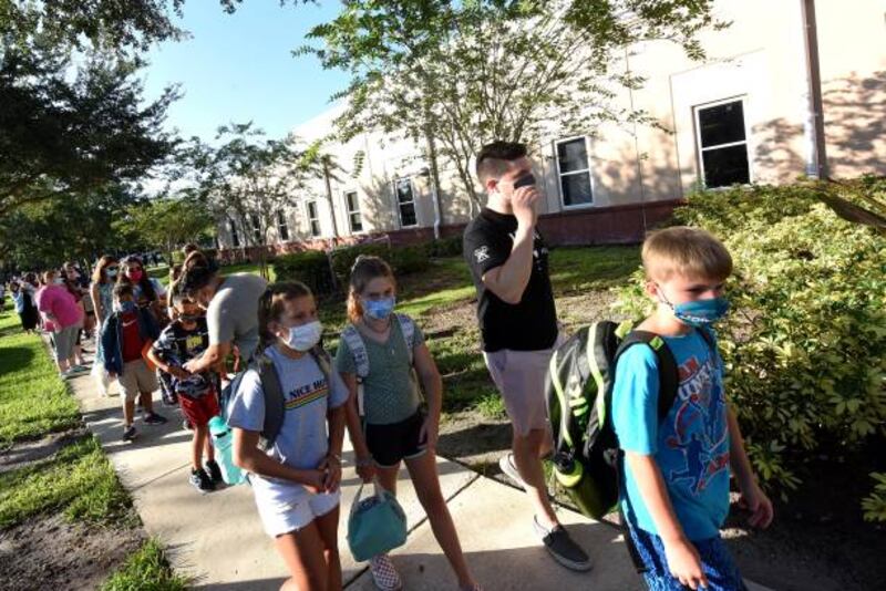 Students wearing face masks arrive with their parents on the first day of classes for the 2021-22 school year at Baldwin Park Elementary School in Florida. Getty Images