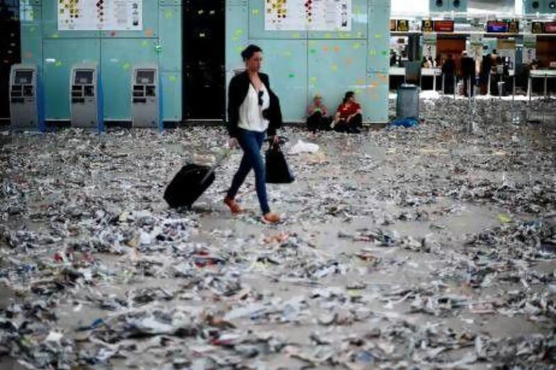 A passenger at Barcelona airport walks through growing piles of litter due to cleaning staff at the airport going on strike over budget cuts.