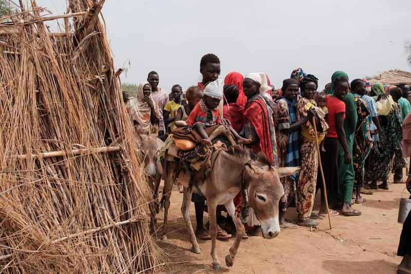 Ali Abdula, 16, carries his two malnourished younger siblings on a donkey past people lining up to register for aid at a camp in Agari, North Kordofan, Sudan. More than 10 million people have been displaced within Sudan since the civil war broke out in April 2023, according to the International Organisation for Migration. AFP
