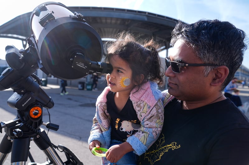 A man and his daughter view the Sun through a telescope ahead of a solar eclipse at the Indianapolis Motor Speedway in Indiana. AP