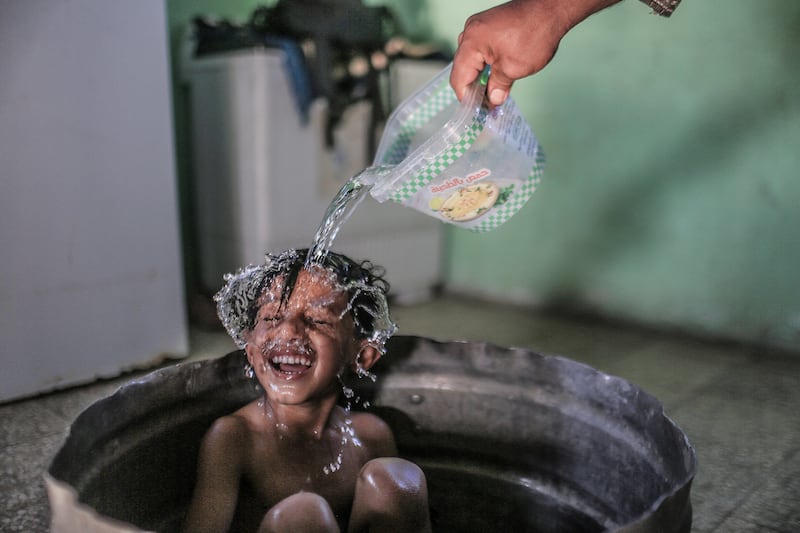 A woman washes her son in their house on the outskirts of Khan Younis refugee camp, Gaza Strip.