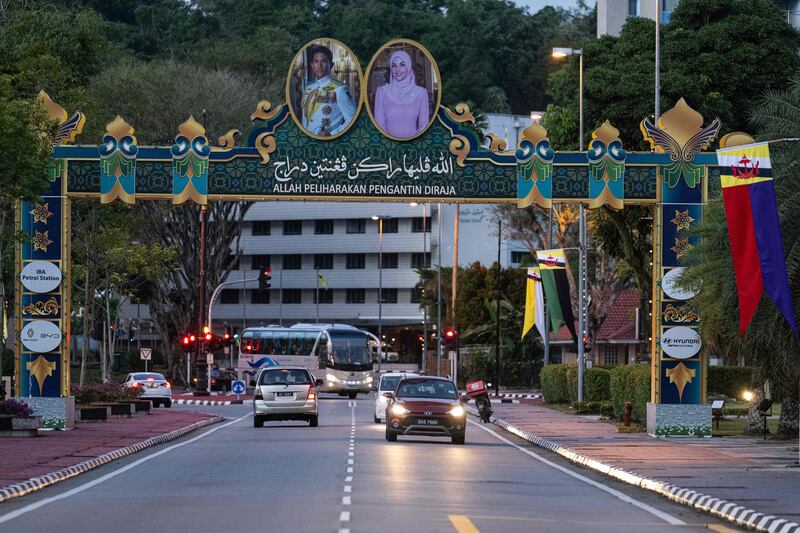 Motorists drive under the portraits of groom Prince Abdul Mateen (L) and bride Anisha Rosnah (R) -- with a slogan in Bahasa Melayu that reads "God protect the royal couple" -- ahead of their wedding in Brunei on Borneo island on January 10, 2024.  Brunei's polo-playing Prince Abdul Mateen, one of Asia's most eligible bachelors, is set to marry his commoner fiancee on January 11 as part of a lavish 10-day celebration in the oil-rich kingdom.  (Photo by Mohd RASFAN  /  AFP)