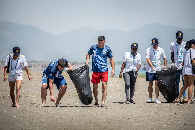 Greek wrestlers Archilleas Chrysidis and Christos Christoforidis (in blue) take part in a beach clean-up at the UWW Beach Wrestling World Series in Sarigerme, Turkey. 