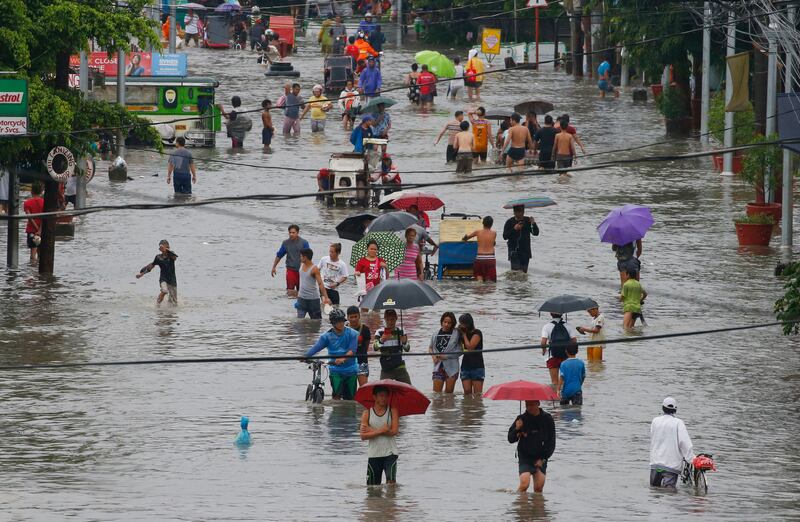 Residents wade through flood water following overnight rains brought on by Tropical Depression "Talim" inundated low-lying areas in Bacoor township, south of Manila in the Philippines. Bullit Marquez / AP Photo