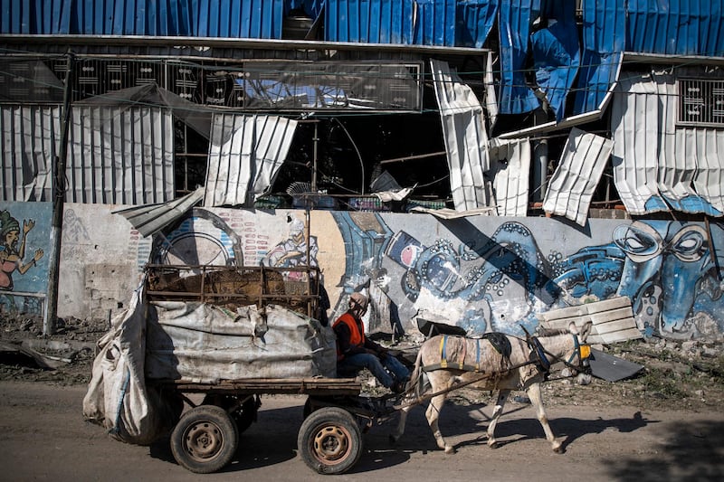 A Palestinian man on a donkey cart passes by a partially destroyed soft drink factory following Israeli airstrikes on Gaza City. AP Photo