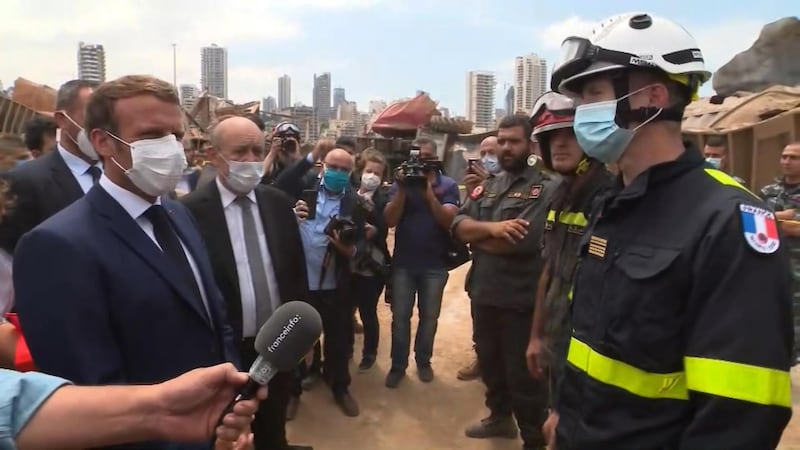 A video grab shows French President Emmmanuel Macron, left, speaking with a member of a French rescue team which arrived overnight to support relief efforts at the port of Lebanon's capital Beirut. AFP