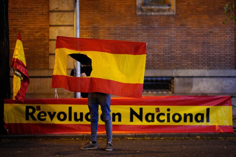 A protester holds a Spanish flag with a hole near the Spanish Socialist Worker's Party HQ while demonstrating against the so-called Amnesty Law in Madrid, Spain. EPA