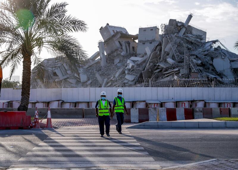 Abu Dhabi, United Arab Emirates, November 28, 2020.  The surrounding areas the morning after the demolition of the Mina Zayed Plaza. Workmen cross the street.
Victor Besa/The National
Section:  National News