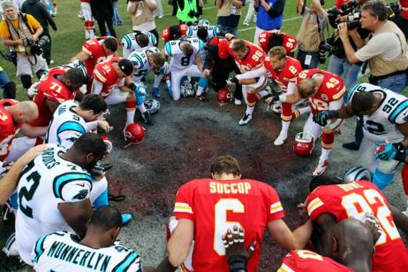Members of the Kansas City Chiefs and Carolina Panthers sides pray together after their match.