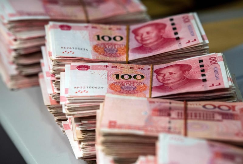 (FILES) This file photo taken on August 8, 2018 shows bundles of 100 yuan (14.6 USD) notes at a bank in Shanghai. China's currency on August 26, 2019 slid to its lowest point in more than 11 years as concerns over the US trade war and the potential for global recession weighed on markets. / AFP / Johannes EISELE
