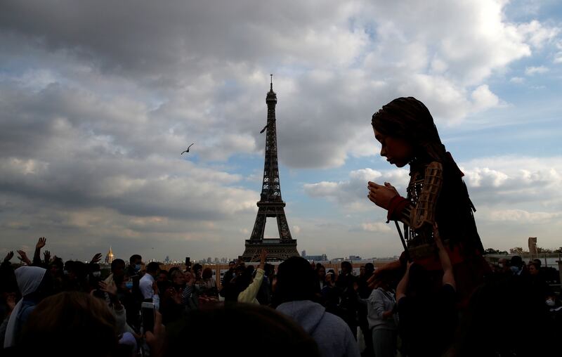 People gather around "Little Amal", a 3. 5 metre tall puppet of a young Syrian refugee girl, as part of its 8,000 km tour across Europe from Turkey to Britain to raise awareness for the plight of young refugees, during a walk at Trocadero square near the Eiffel tower in Paris, France. Reuters