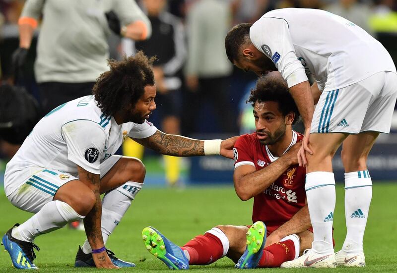 Salah holds his shoulder as Real Madrid players check on him.  Georgi Licovski / EPA