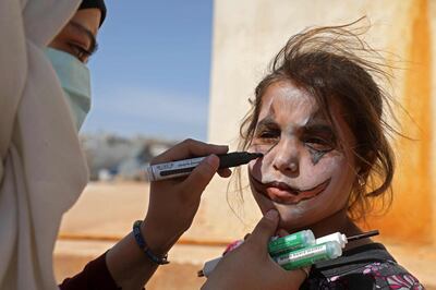 Displaced Syrian artist Ayat al-Aziz paints the face of a girl during a COVID-19 awareness campaign at the Bardaqli camp in the town of Dana in Syria's northwestern Idlib province, on April 20, 2020.  / AFP / AAREF WATAD
