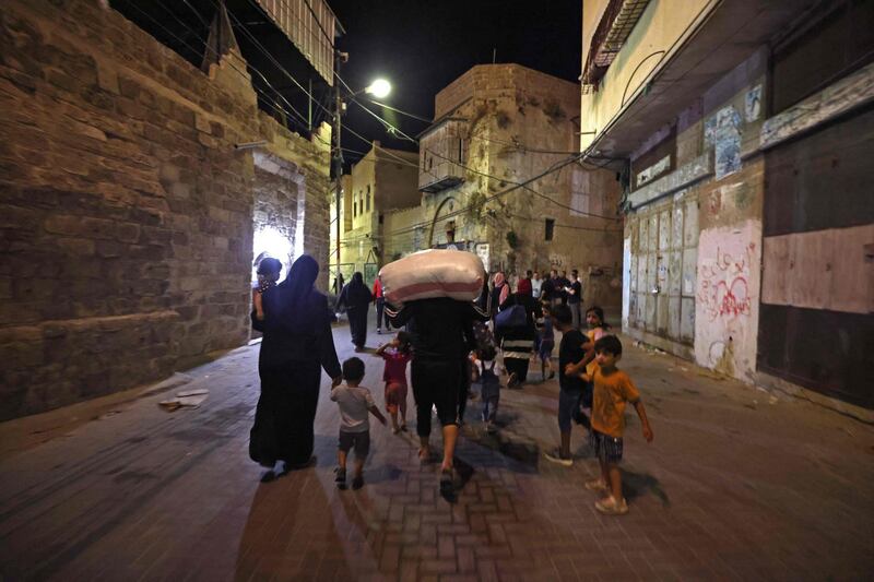 Palestinian families are pictured in a street after evacuating their homes east of Gaza City on May 13, 2021, due to heavy shelling by the Israeli military.  / AFP / MOHAMMED ABED
