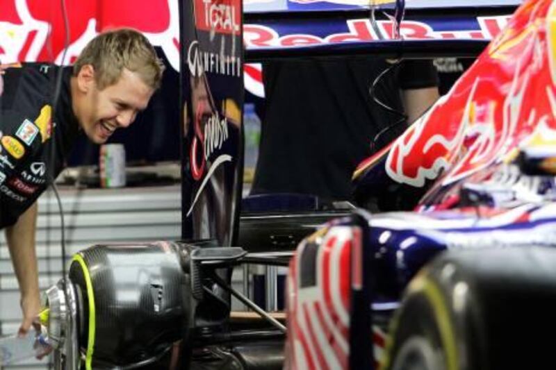 Red Bull Formula One driver Sebastian Vettel of Germany smiles as he chats with mechanics working on his car in the garage at the Marina Bay street circuit of the Singapore F1 Grand Prix September 22, 2011.    REUTERS/Tim Chong (SINGAPORE  - Tags: SPORT MOTOR RACING)   *** Local Caption ***  SGP224_MOTOR-RACING_0922_11.JPG