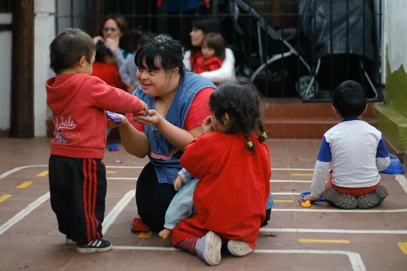 Kindergarten teacher Noelia Garella, centre, who was born with Down Syndrome, plays with children at the Jeromito kindergarten in Cordoba, Argentina on September 29, 2016 where she teaches. Diego Lima / AFP