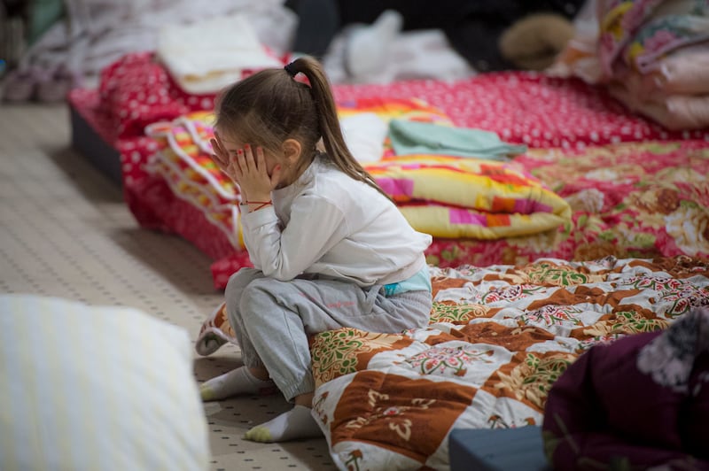 A child refugee who fled the conflict in Ukraine covers her face in the event hall of a hotel offering shelter in Siret, Romania. AP