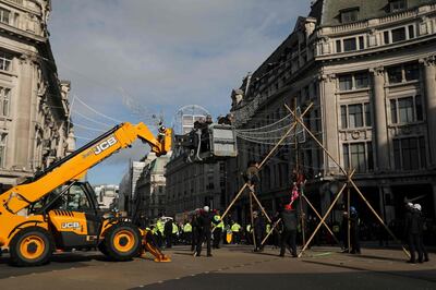 Police use heavy machinery as they remove a climate activist perched on a makeshift structure in Oxford Street, during the twelfth day of demonstrations by the climate change action group Extinction Rebellion, in London, on October 18, 2019. The Extinction Rebellion pressure group has been staging 10 days of colourful but disruptive action across London and other global cities to draw attention to climate change. / AFP / ISABEL INFANTES
