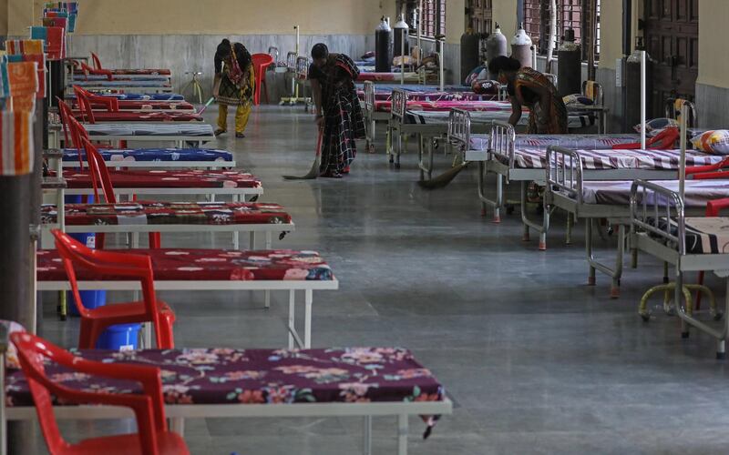 Workers clean the floor near the beds inside a newly opened Covid-19 centre in Mumbai. EPA