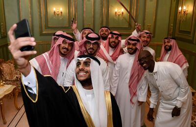 Saudi groom Basil Albani poses for a selfie with his friends during his wedding at his home in the Red Sea resort of Jeddah on September 6, 2018. It was a Saudi wedding like any other -- clutching a decorative sword, the groom bobbed and swayed in a traditional dance. But there was one striking difference -- a tiny guest list. Weddings in the oil-rich kingdom are typically lavish affairs, with a bulging guest list which is seen both as a social obligation and a symbol of affluence.
 / AFP / Amer HILABI
