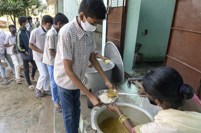 Staff serve midday meals to pupils at a government high school on the outskirts of Hyderabad in India, as schools reopened after months closed due to the Covid-19 pandemic.  AFP