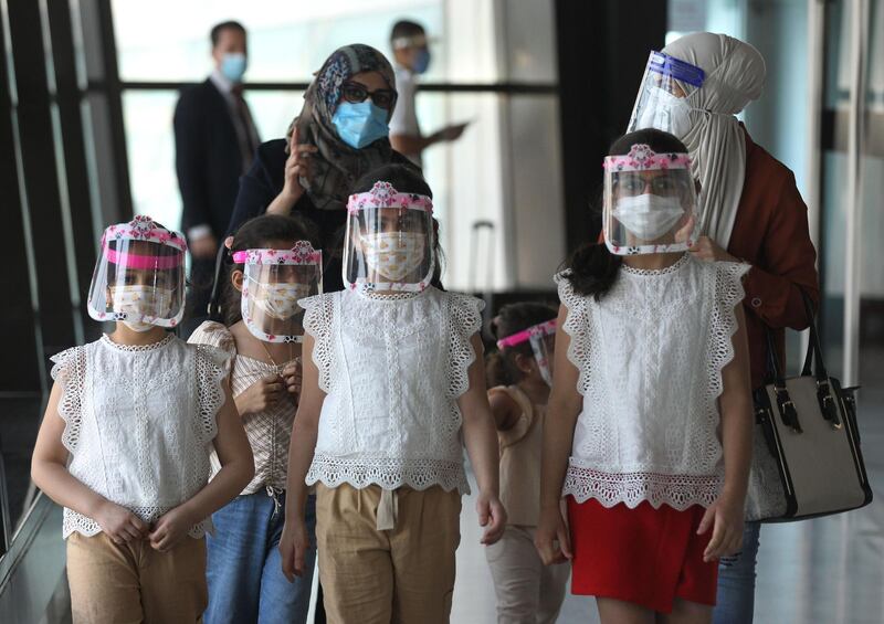 A family wearing protective masks walk at the departure hall. AFP