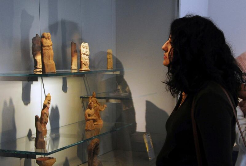 In this photo released by the Syrian official news agency SANA, a visitor looks at ancient artifacts during the reopening ceremony for  Syria's National Museum, in Damascus, Syria, Sunday, Oct. 28, 2018. Syrian officials, foreign archeologists and restoration specialists attended the Sunday reopening ceremony in the heart of Damascus more than six years after the prominent institution was shut down and emptied as the country's civil war encroached on the capital. (SANA via AP)