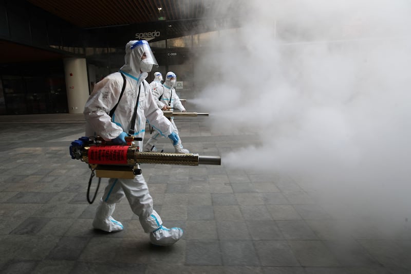 Workers spray disinfectant outside a shopping mall in Xi'an, northern China. AFP