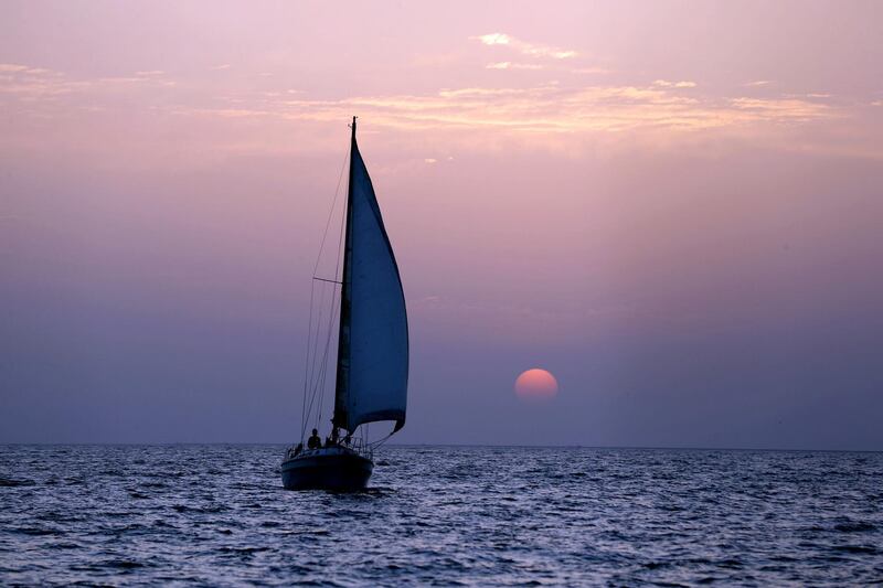Dubai, United Arab Emirates - May 14, 2019: The sun sets behind a sailboat during Ramadan. Tuesday the 14th of May 2019. Dubai. Chris Whiteoak / The National