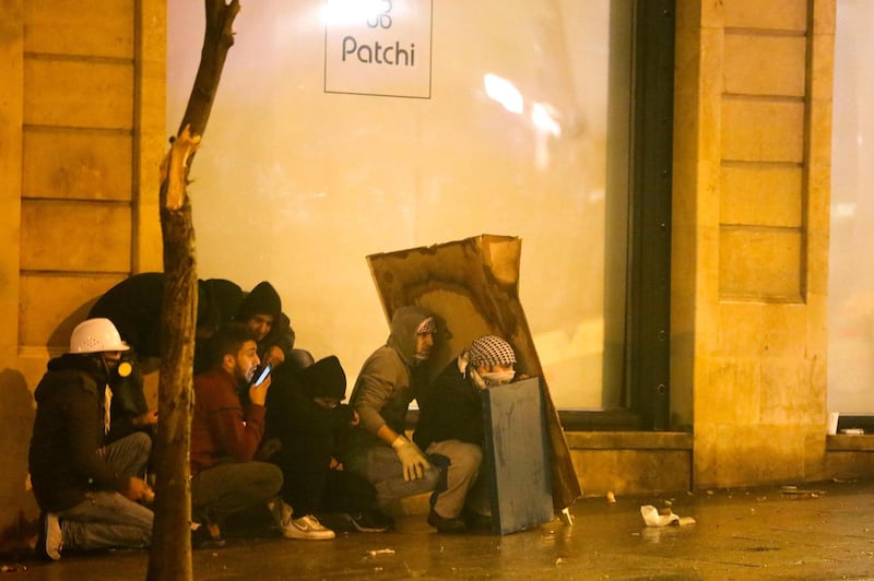 Lebanese protesters take cover amid clashes with riot police guarding a road leading to parliament in central Beirut.  AFP