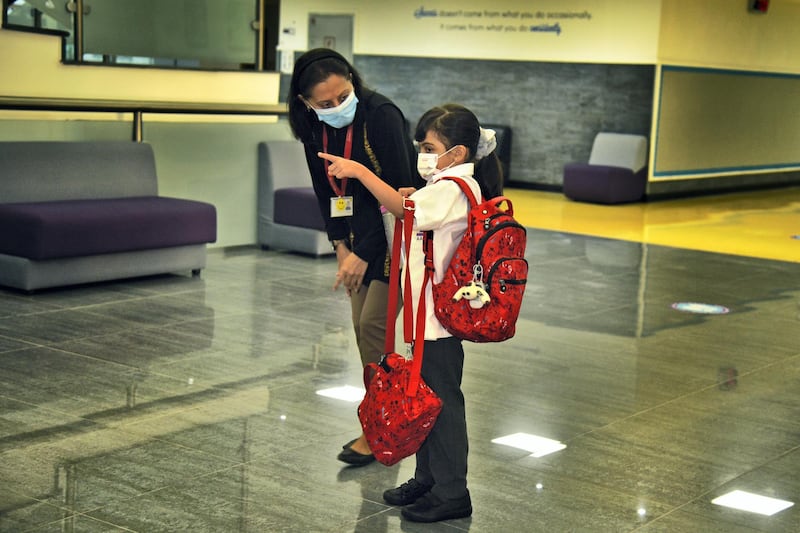 Member of Al-Mizhar American Academy for Girls assists a student wearing protective masks as they return to school after months on Sunday, Aug. 30, 2020, in Dubai, UAE. (Photos by Shruti Jain - The National)