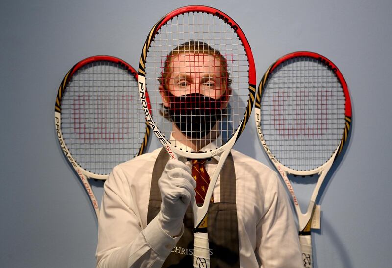 A Christie's employee poses with Swiss tennis Roger Federer's  racket used at the London Olympics 2012 at Christie's in London last month during a live auction.