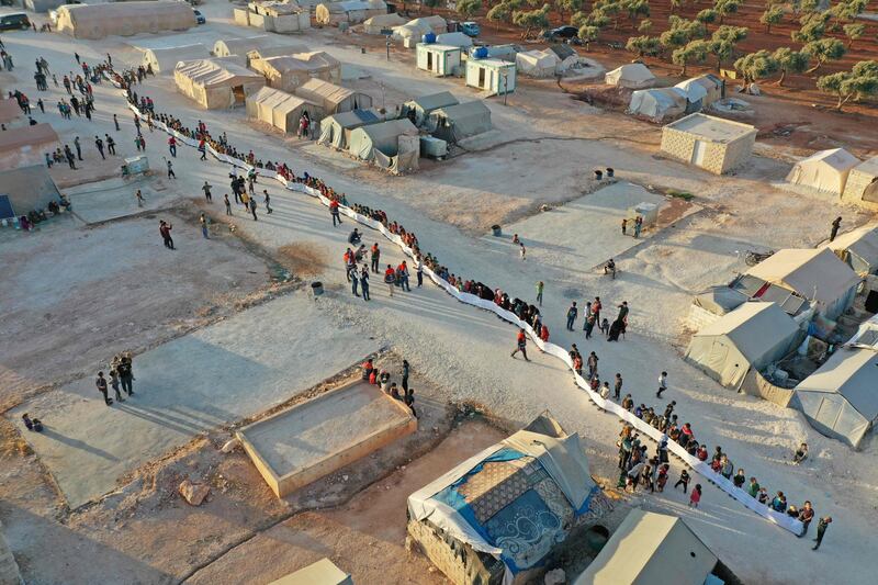 An aerial view of displaced Syrian children with a banner they produced for the International Day of Peace at a camp in Maarrat Misrin in Idlib province, Syria.