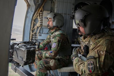 US Master Sgt Justin Kay with an Afghan aerial gunner during a training mission aboard an MI-17 helicopter near Kandahar, Afghanistan, in March 2016. Reuters